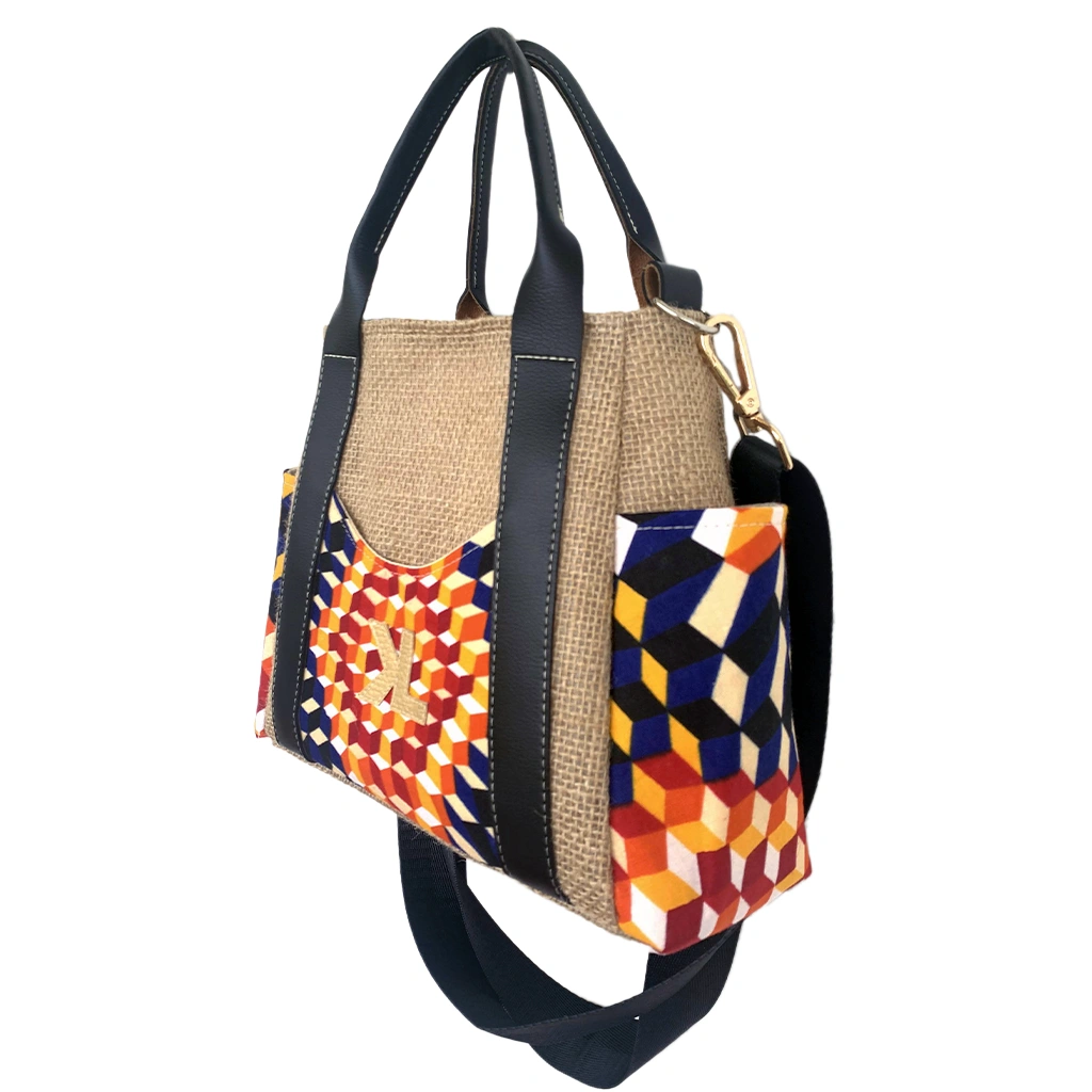 Kalia Graphik 3 Sac à main Kalia Mini Graphik en toile de jute beige, avec poches latérales et frontale en tissu géométrique multicolore et anses en simili cuir noir.
