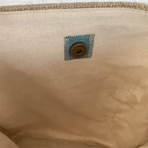 L'intérieur de la besace KALIPSA by KerdeL Créations, en toile de jute, simili-cuir marron, suédine turquoise. Décoration feuilles tropicales.