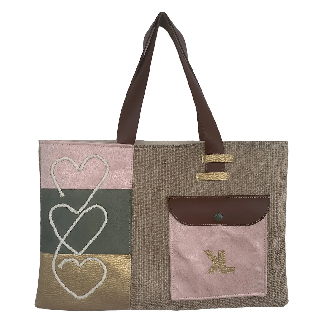 Vue de face du sac cabas artisanal KUBÉA en jute, suédine et simili cuir, avec broderie cœur et poche contrastée, fait main en Guadeloupe.