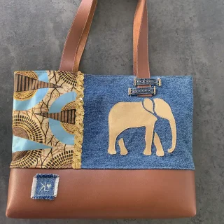 Sac cabas en jean, wax et simili cuir marron, décoré d’un éléphant doré en appliqué, de galons dorés et de détails artisanaux cousus main.